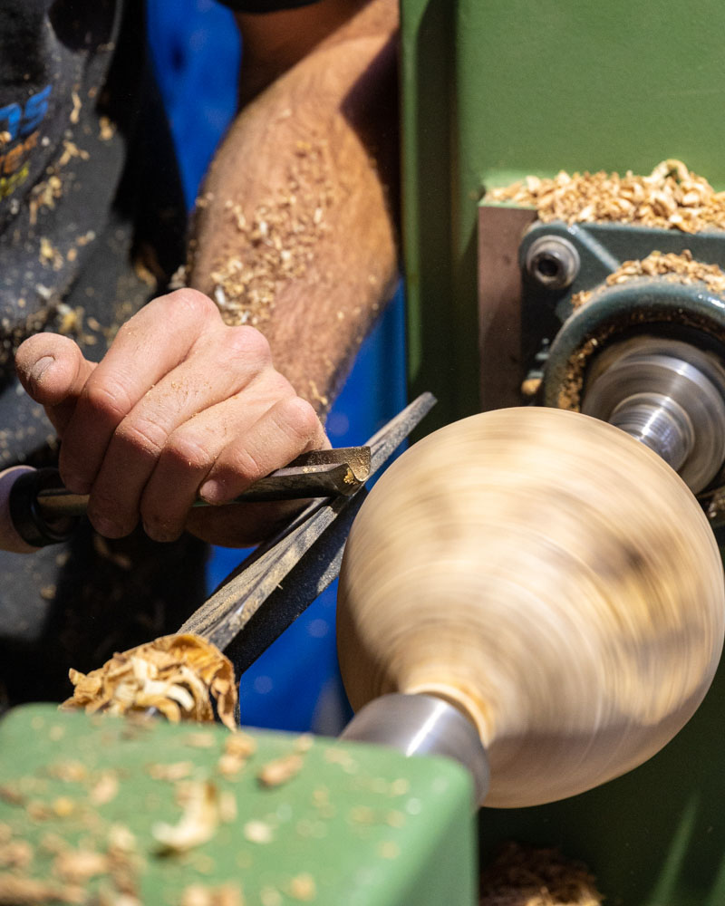 photos gros plan montrant les mains travaillant le bois sur le tour