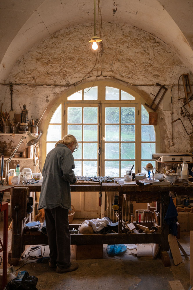 Pascaline à l'oeuvre sur son établi devant la baie vitrée